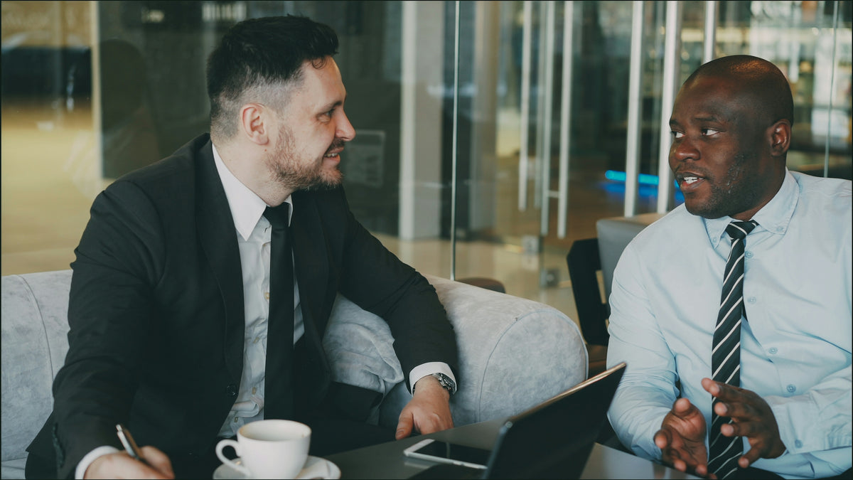 Two businessmen in suits talking at a table